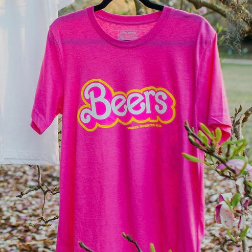 Pink tee shirt. Front reads “Beers” in pink and yellow, style of the Barbie doll font. Beneath "beers" is written "women invented beer"